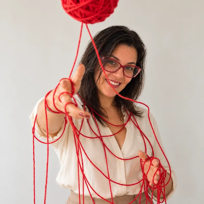 Criadora do Jardim de Amigurumi, segurando um novelo de fio vermelho